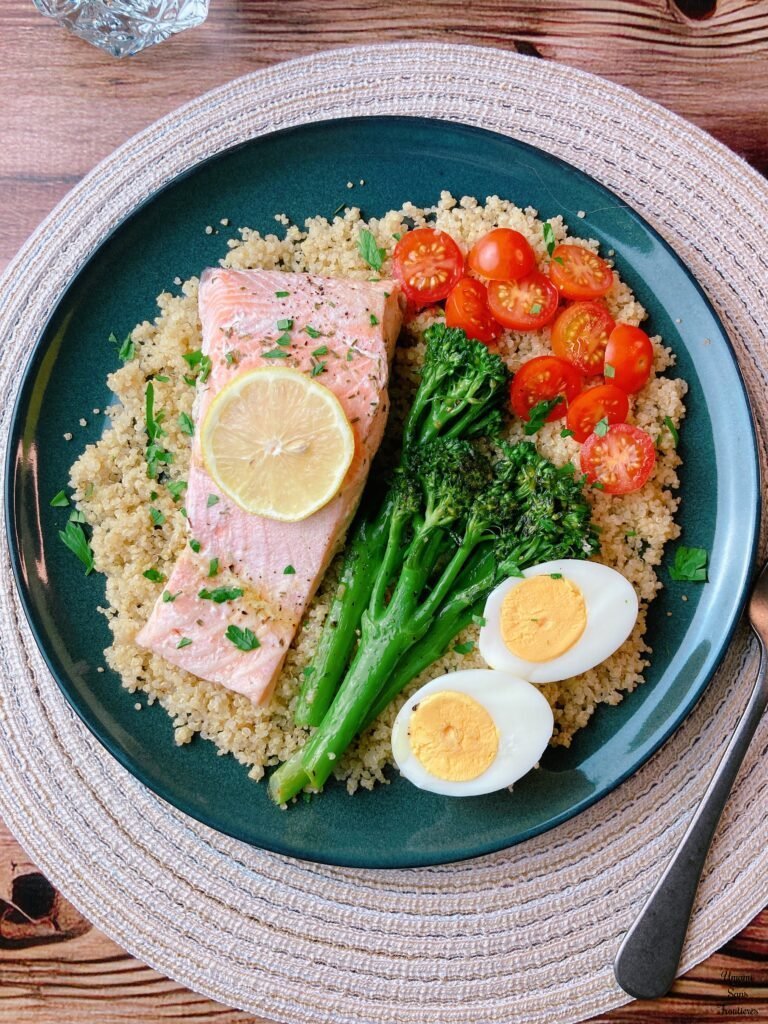 porched salmon and quinoa plate with lemon soy sauce fork water